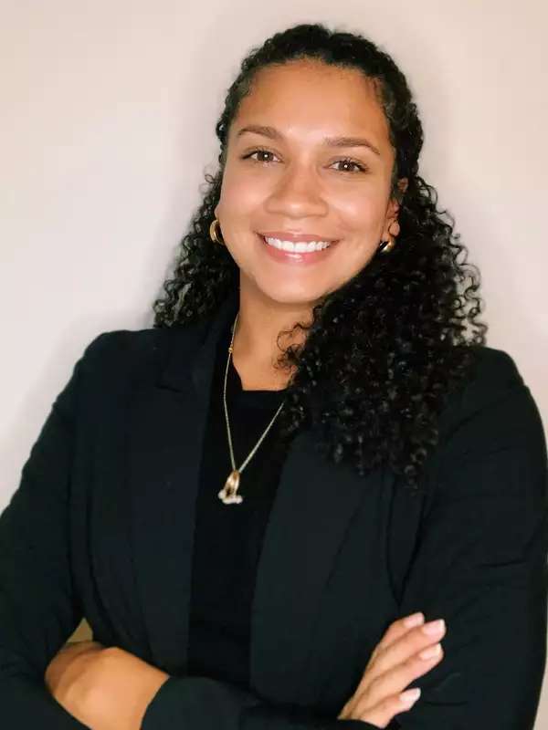 Photo of Domonique Reed smiling and dressed in a black suit